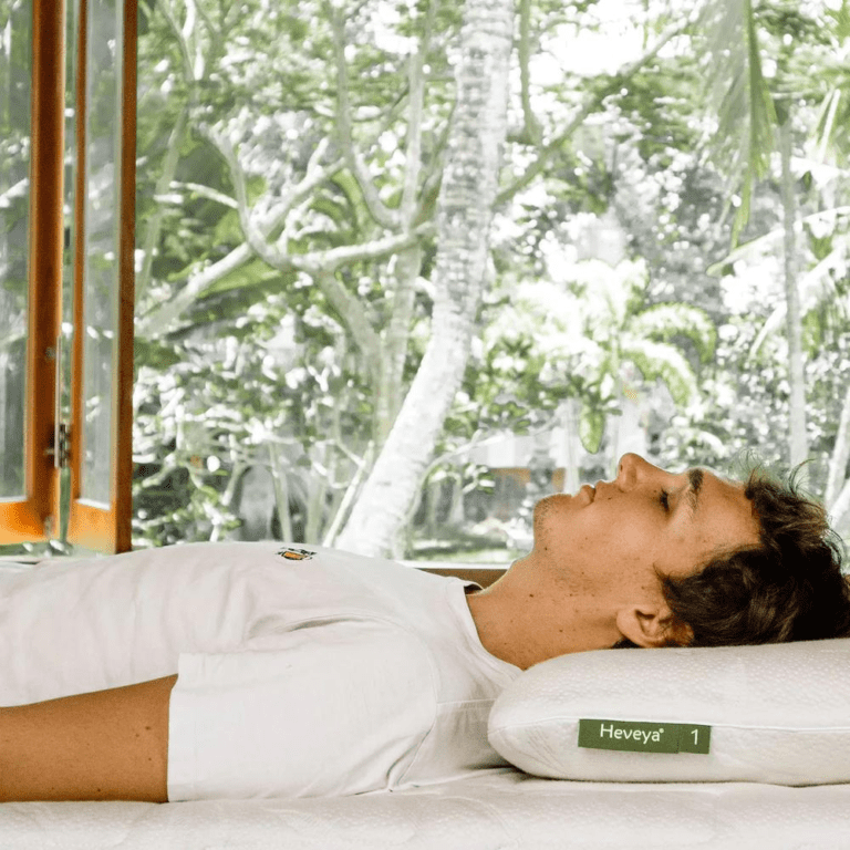 Man sleeping peacefully on his back on a soft, thin Heveya organic latex pillow. Ideal for comfortable back sleep and neck support.