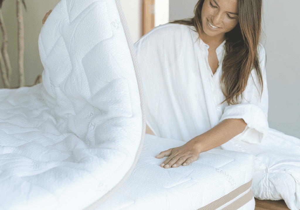 A woman explores the customizable comfort of the Heveya® Natural Latex Mattress III. The easy-to-remove top layer reveals the supportive middle layer. Crafted from 100% natural latex, each layer offers exceptional comfort and targeted support.