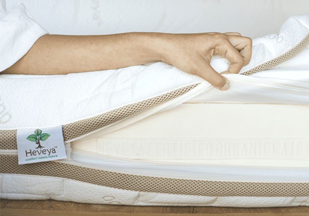 Close-up of a hand unzipping the side of a Heveya mattress, revealing the layers of natural latex inside.