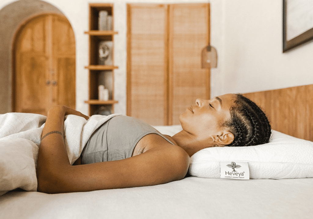 Woman enjoying a restful sleep on a Heveya® Natural Organic Latex Pillow. The pillow's ergonomic design, made from 100% organic latex, promotes spinal alignment and pressure relief