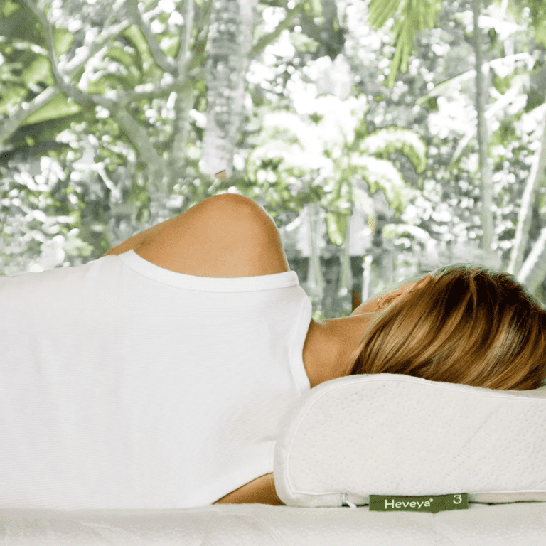 Woman experiencing a comfortable night's sleep on her side with the Heveya Contoured Organic Latex Pillow. Provides ergonomic support for the neck and shoulders.