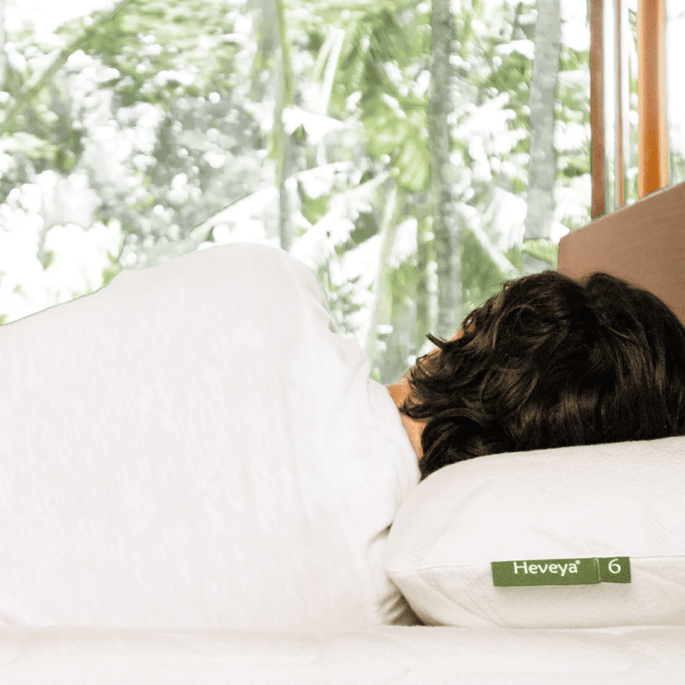 Man experiencing a comfortable night's sleep on his side with the Heveya Extra Firm Pillow for Side Sleepers. This ultra-supportive organic latex pillow promotes optimal spinal alignment for broad shoulders