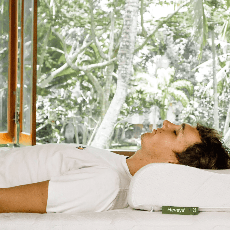 Man enjoying a restful sleep on his back with the Heveya Contoured Organic Latex Pillow. The medium-density organic latex offers plush comfort and pressure relief.